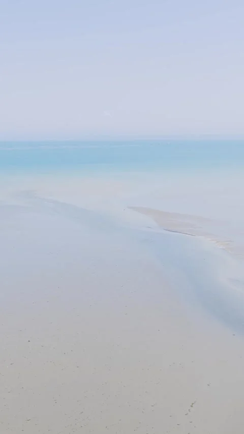 Aerial view of a serene, empty sandy beach and calm turquoise sea at Binic Stock Footage 346663257