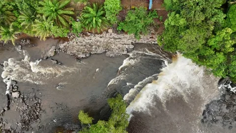 Aerial view of a serene waterfall surrounded by lush greenery and dense forest. Stock Footage 337992453