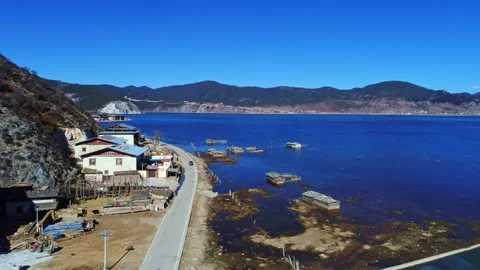 Aerial view of shallow beach lakeside road waterfront houses mountain lake Stock Footage 337923612