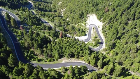 Aerial view of sharp mountain hairpin road crossing dense forest slope Stock Footage 343948233