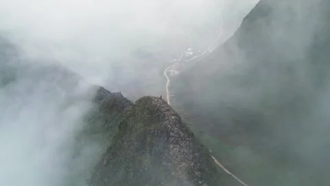 Aerial View of Sharp Mountain Ridge Shrouded in Fog with Lone Hiker Exploring Stockbeeldmateriaal 334339635