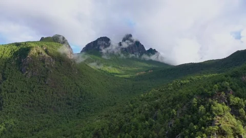 Aerial view of sharp rocky peaks emerging from green misty mountains in Daocheng Video stock 336698815