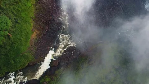 Aerial view showcasing a powerful waterfall cascading down rocks surrounded by Stock Footage 307890602