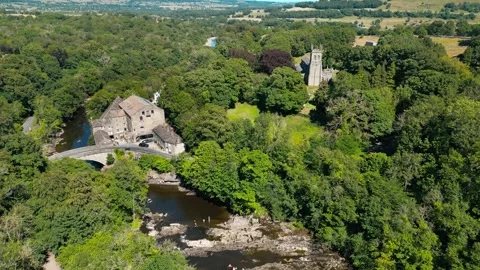 Aerial view shows ancient stone buildings nestled in lush greenery. Yorkshi.. Stock Footage 346287855