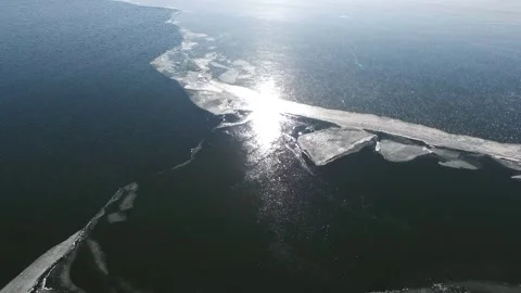 Aerial view shows a frozen lake surface broken into ice plates - Canadian Lake Stock Footage 339347360