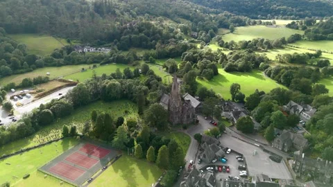 Aerial view shows green fields, trees, and a stone church Stock Footage 345521108