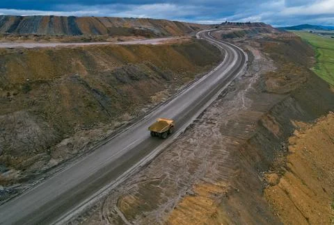 Aerial view shows large dump truck transporting materials on a wide dirt road at Stock Photos