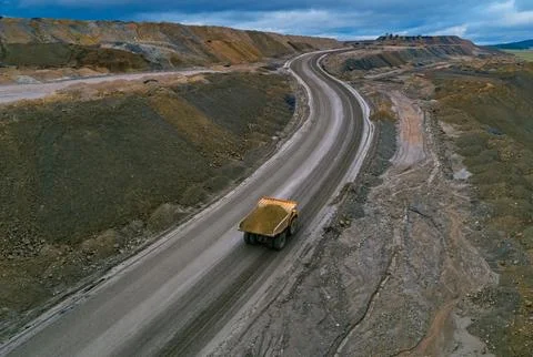 Aerial view shows large dump truck transporting materials on a wide dirt road at Stock Photos