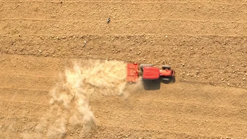 An aerial view shows a red tractor pulling a cultivator across a dry. Stock Footage 274938423