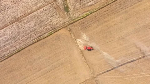 An aerial view shows a red tractor pulling a cultivator across a dry. Stock Footage 274938574