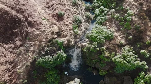 Aerial view shows a small waterfall flowing through a canyon 库存影片 342931930
