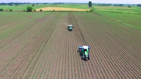 Aerial view shows two green tractors plowing cultivated fields - Diesel Tractor Stock Footage 339488389
