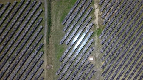 An aerial view shows a vast array of solar panels reflecting sunlight from a Stock Footage 334268064