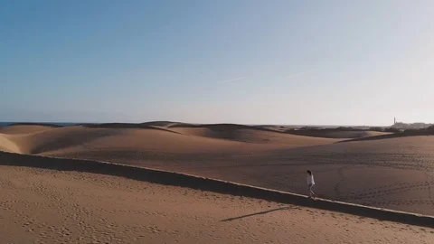 Aerial view is a side view of the dune along which a beautiful young woman walks Stock Footage 113230385