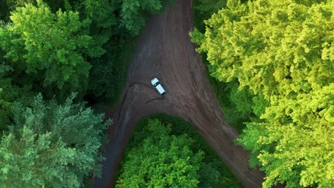 Aerial view of a silver car driving on a winding dirt road through... Stock Footage 341894255