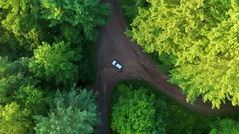 Aerial view of a silver car driving along a winding dirt road through... Stock Footage 341894261
