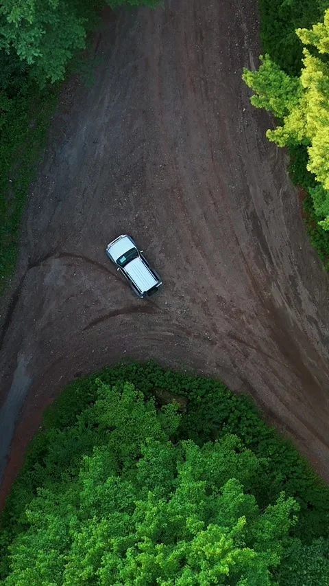 Aerial view of a silver car driving on a winding dirt road through... Vídeo Stock 344332635