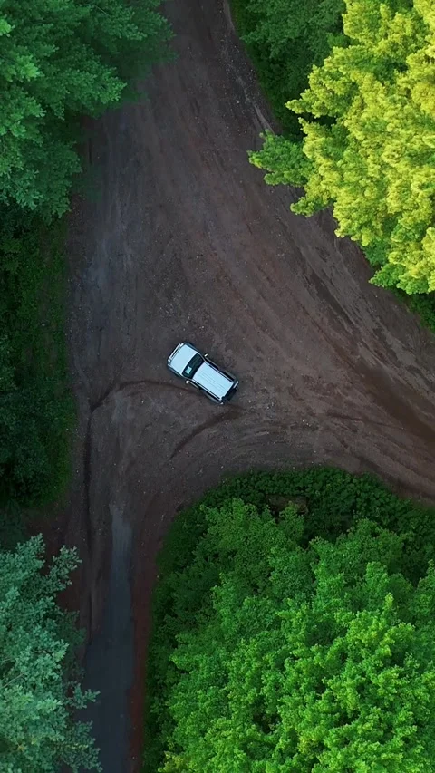 Aerial view of a silver car driving along a winding dirt road through... Vídeo Stock 344332640