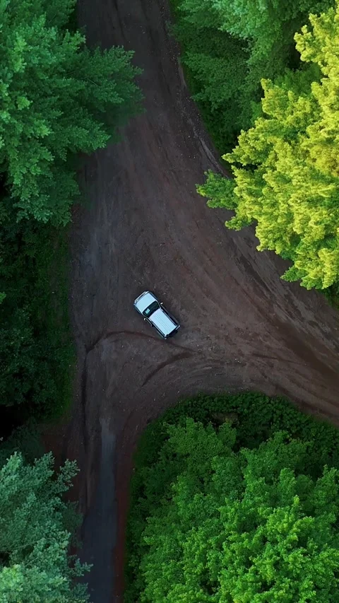 Aerial view of a silver vehicle navigating a winding dirt road through... Vídeo Stock 344332642