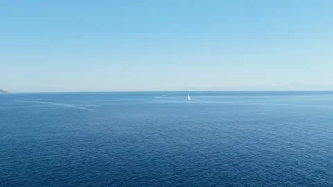 Aerial view of a single sailboat sailing on the calm, deep blue waters of the Stock Footage 346694405