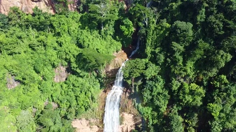Aerial view of a single waterfall cascading down a rocky cliff surrounded by Stock Footage 316961798