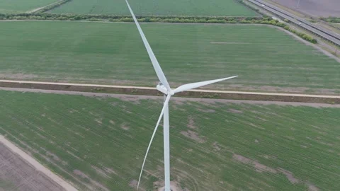 Aerial view of a single wind turbine rotating its large blades over green Stock Footage 337885239