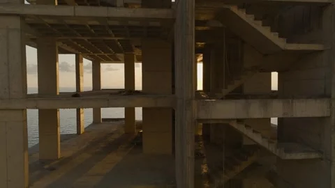 Aerial View: The skeleton of a multi-story building stands against the ocean Stock Footage 296078403