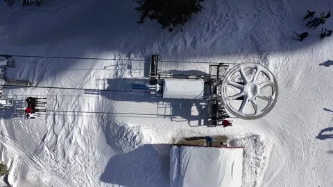 Aerial view of a ski lift operating at a snowy mountain resort, with skiers Stock Footage 344095242