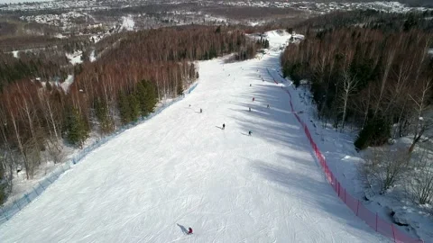 Aerial view on a ski slope surrounded with trees, people snowboarding and skiing Video stock 153717120