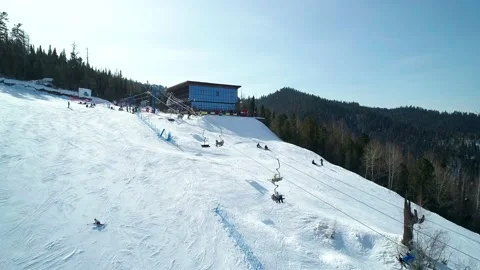 Aerial view ski slope surrounded with trees, people snowboarding and skiing down Stock Footage 153727576