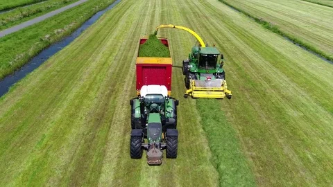 Aerial view from sky flying backwards in front of combine harvester and tractor Stock Footage 77190864
