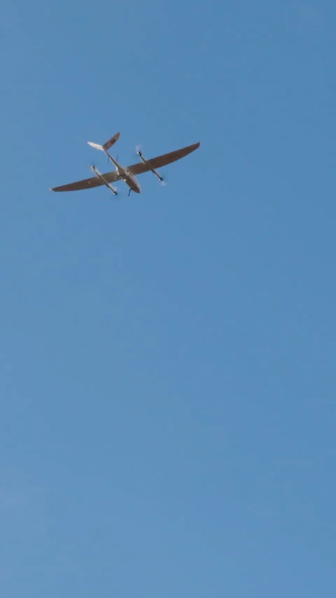 Aerial view of a sleek drone flying against a bright blue sky, showcasing its Stock Footage 314307264
