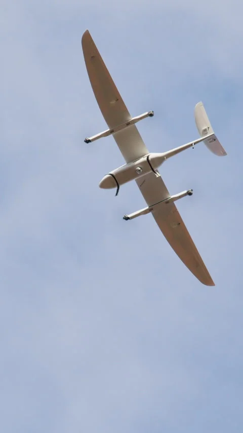 Aerial view of a sleek drone soaring through a clear blue sky, showcasing its Stock Footage 314269614