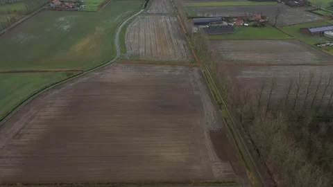 Aerial view slowing moving down above a landscape of meadows and brown fields Stock Footage 142750051