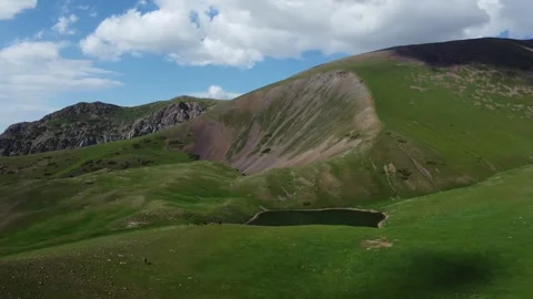 Aerial view of small alpine lake nestled in green mountains of Kazakhstan Vídeo Stock 337129636