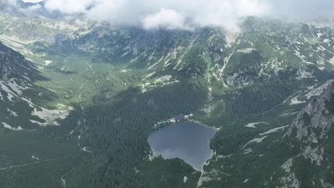 Aerial view of a small alpine lake below mountain peaks Stock Footage 345169215
