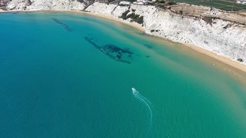 Aerial view of a small boat navigating through clear turquoise waters Stock Footage 345125172