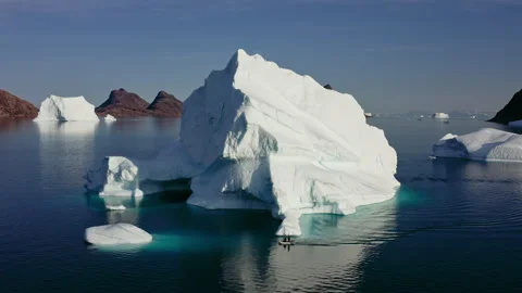 Aerial View of Small Boat Passing Massive Iceberg - Greenland Stock Footage 346189244