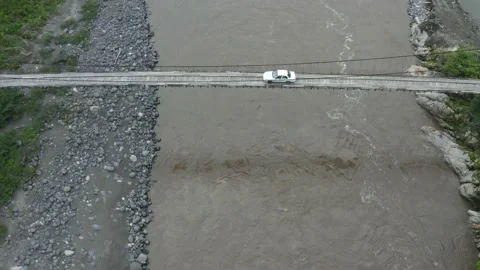 Aerial view of a small bridge over a large river while a car drives over it Stock Footage 143676472