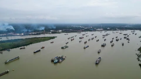 Aerial view of small cargo ships navigating through a wide river. The calm water Stock Footage 287766947