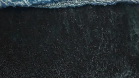 Aerial view of small coastal waves over black sand beach. Nusa Bali, Indonesia Stock Footage 316650485