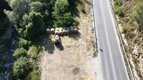 Aerial View of Small Farm Tractor Parked Beside Round Hay Bales Near Country Roa 動画素材 343130713