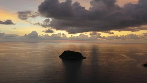 Aerial view of small island at sunset with dramatic clouds and ocean reflections Видео 342312925