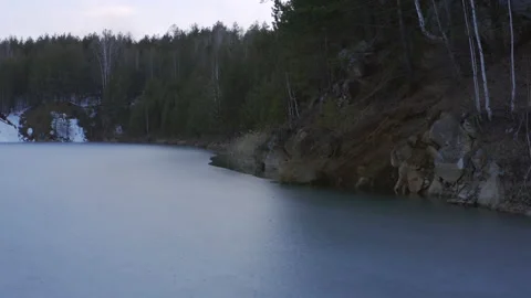Aerial view of a small lake with a thin layer of ice in the forest. Stock Footage 132712754