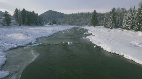 Aerial view of the small river in winter among the forest and mountains 4K Stock Footage 57253247