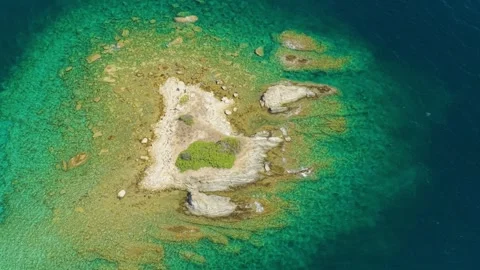 Aerial view of a small rocky islet surrounded by crystal-clear turquoise waters Stock Footage 346678545