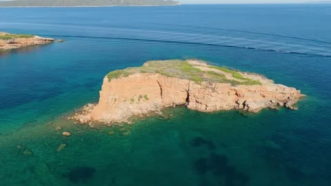 Aerial view of the small rocky islet of Kokkinokisi surrounded by clear Stock Footage 346687298