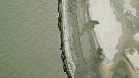Aerial view of small sea waves crashing onto a geo-bag barrier along the shoreli Stock Footage 287778889