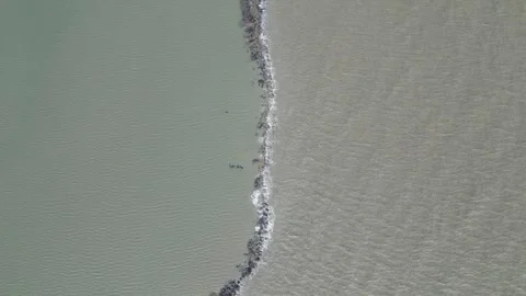 Aerial view of small sea waves crashing against a barrier, with water Stock Footage 287782071