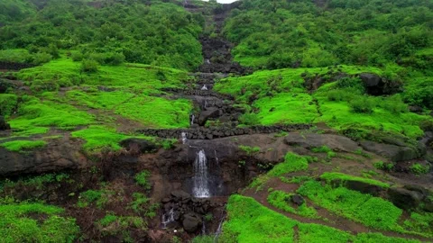 Aerial View of a Small Waterfall Cascading Through Lush Green Mountains Видео 342701538